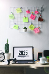 Office desk with 2025 loading bar on laptop screen for happy new year concept