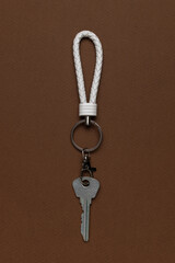 Minimalist Key Setup with White Braided Loop Against Brown Background