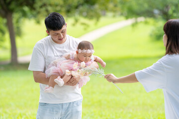 Fototapeta premium A Taiwanese couple in their 20s and their 7-month-old baby celebrate a birthday in a vast green park in Yilan County, Taiwan.