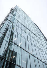 A picture of a tall building with numerous windows and a prominent clock. This image can be used to represent urban architecture, city life, time  Modern Architecture detail Abstract Background  