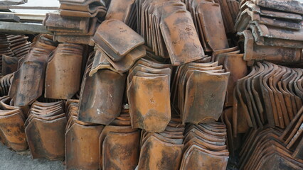 A number of orange tile roofs are neatly arranged on the side of the road on a sunny day.
