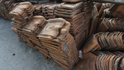 A number of orange tile roofs are neatly arranged on the side of the road on a sunny day.
