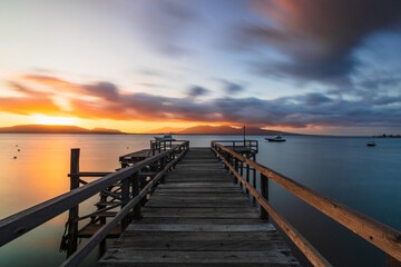 Fototapeta premium Beautiful sunrise view with wooden jetty at Pantai Dermaga Cinta, Banyuwangi, Indonesia. Nature composition. Long Exposure.