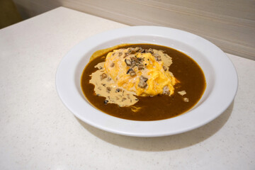 Creamed Mushroom Omelet Curry.   Curry rice served in white ceramic plate. Spicy food in Japanese restaurant. © chadchai