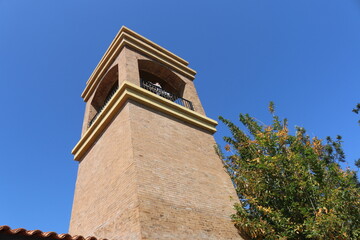 Brick Tower with Blue Sky Background and Greenery