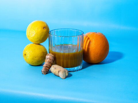 glass of jamu against orange, ginger and lemon