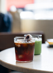 A clear glass of iced- lychee americano coffee with topped lychee fruit, it’s a refreshing beverage of two distinct flavors.