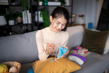Obraz premium Happy young female&nbsp;asian woman hands crochets handmade crocheting supplies assorted yarn hook knitting handmade for crochet handcraft hobby for relax&nbsp;on sofa