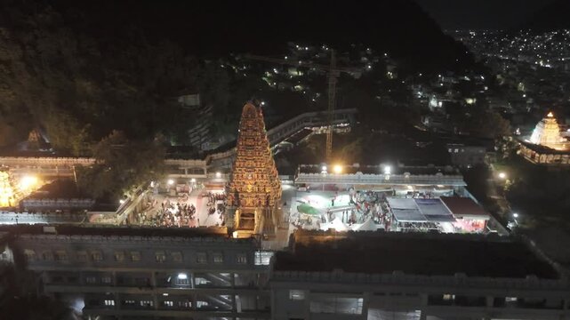An aerial video of Kanaka Durga Temple in Vijayawada at night.The temple's golden gopuram, illuminated by countless lights, would create a celestial glow against the inky blackness of the sky.