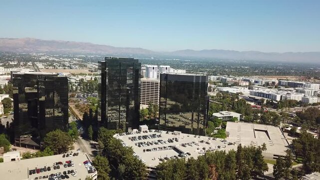 Aerial approaching shot of mirrored AIG Capital Service buildings during sunny day in autumn. Los Angeles City Suburb and mountains in background. Wide shot.