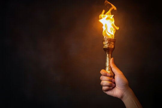 A person holds a glowing torch illuminating the darkness. Signifying leadership, guiding light, and showing the way forward.