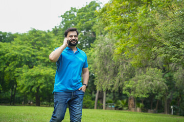 Young indian man talking on the phone outdoor at summer park.