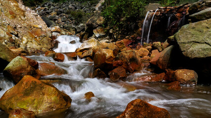 Obraz premium The hot water flowing from the bamboo merges with the cold water river that comes from the waterfall above it, located in the middle of the Mount Halimun Salak National Park forest, Bogor, Indonesia.
