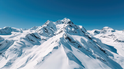 Majestic snow covered peaks rise against clear blue sky, showcasing stunning beauty of winter landscapes. sharp mountain ridges create breathtaking view of natures grandeur