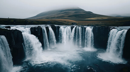 Fototapeta premium Majestic waterfall cascading down rocky cliffs, surrounded by lush greenery and misty mountains. serene atmosphere evokes sense of tranquility and awe