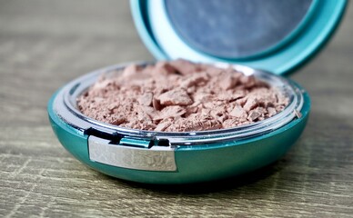 Crushed destroyed compact powder in round box container isolated on horizontal ratio brown wooden...