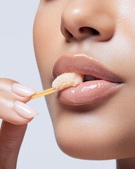 Naklejka premium Close-up of a woman applying lip scrub on smooth lips with a wooden stick.