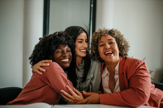 Embraced small group of business women hugging each other and smiling during a business meeting