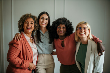 Embraced team of business people standing together in the bright office. Group business portrait image