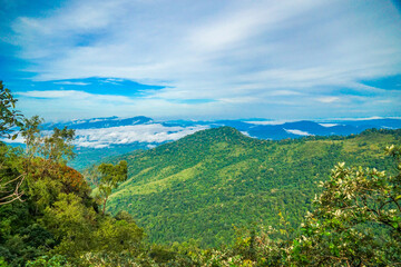 Obraz premium A breathtaking view of lush green hills under a vibrant blue sky with fluffy clouds.