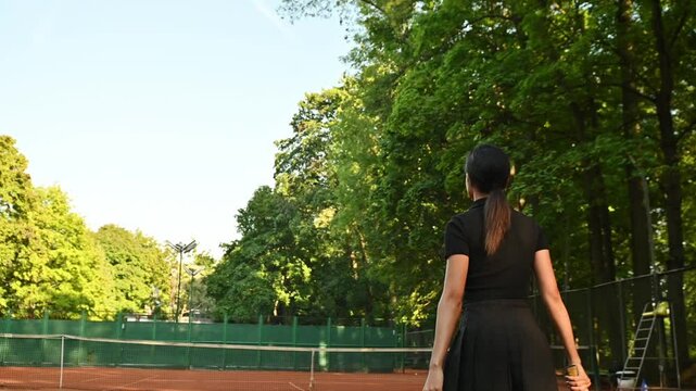 A tennis player plays sports on a tennis court . The athlete trains in tennis. An African girl plays tennis. 