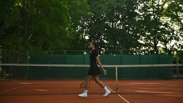 A tennis player plays sports on a tennis court . The athlete trains in tennis. An African girl plays tennis. 