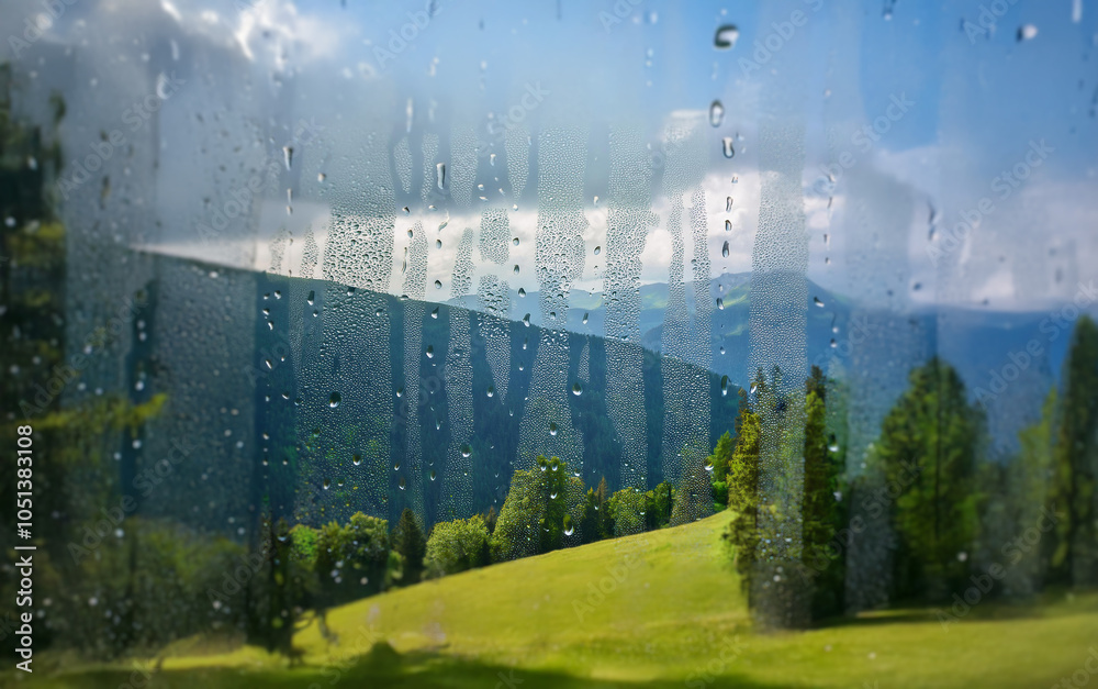 Poster A view of rolling hills and a mountain range is seen through a window covered in raindrops.