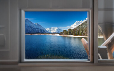 A small window reveals a breathtaking mountain lake scene, with snow-capped peaks and a serene blue expanse of water.