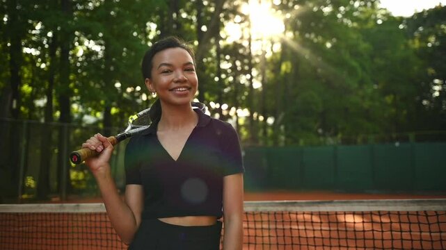 A tennis player plays sports on a tennis court . The athlete trains in tennis. An African girl plays tennis. 