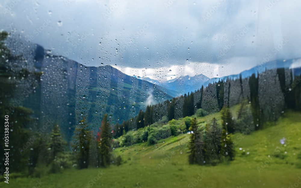 Poster A view of a mountainous landscape through a window with raindrops.