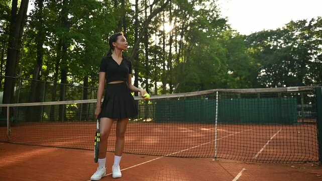 A tennis player plays sports on a tennis court . The athlete trains in tennis. An African girl plays tennis. 