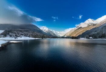 Obraz premium A serene mountain lake with snow-capped peaks reflecting in the still water.