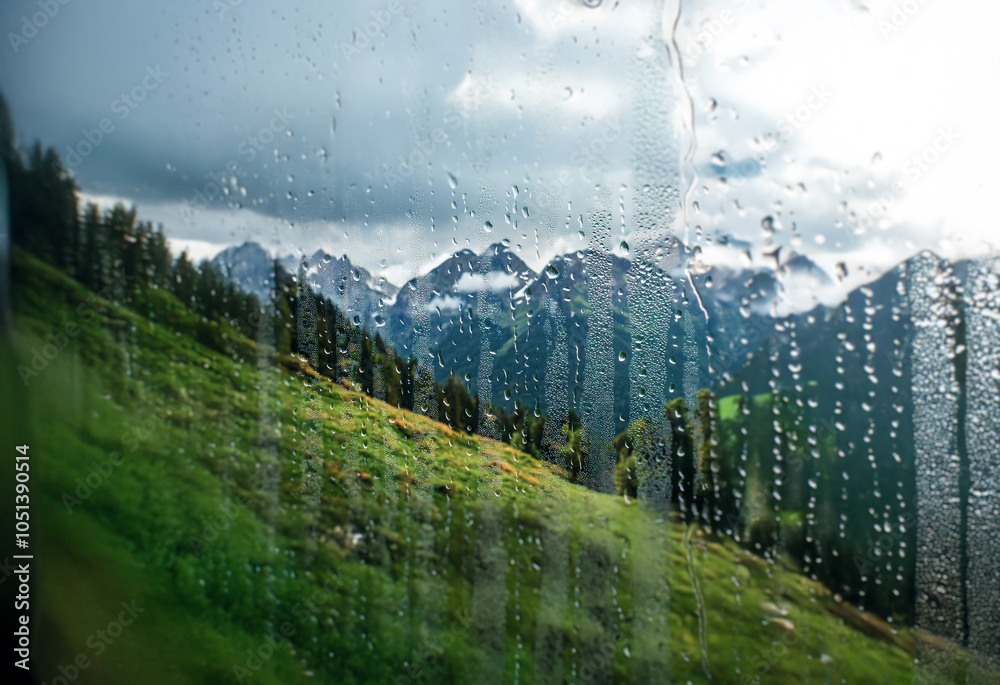 Poster a view of a mountain range through a rain-streaked window.