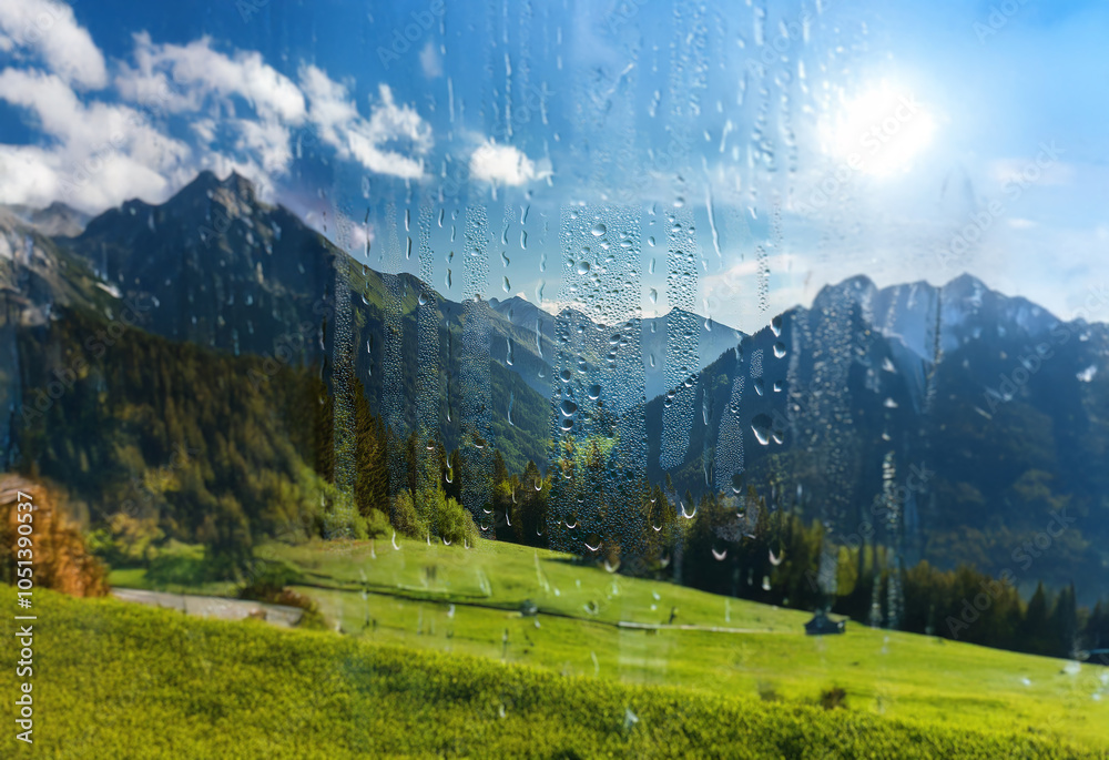 Poster A view of a mountain range through a window with raindrops.