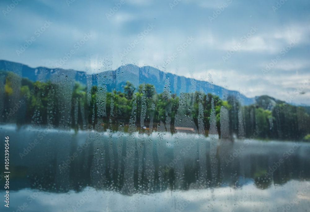 Poster A view of a lake and mountains through a window with condensation.