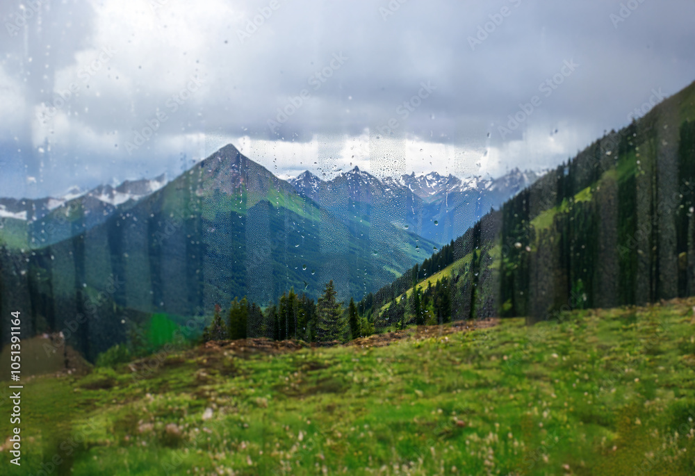 Poster A view of a mountain range through a window with raindrops on the glass.
