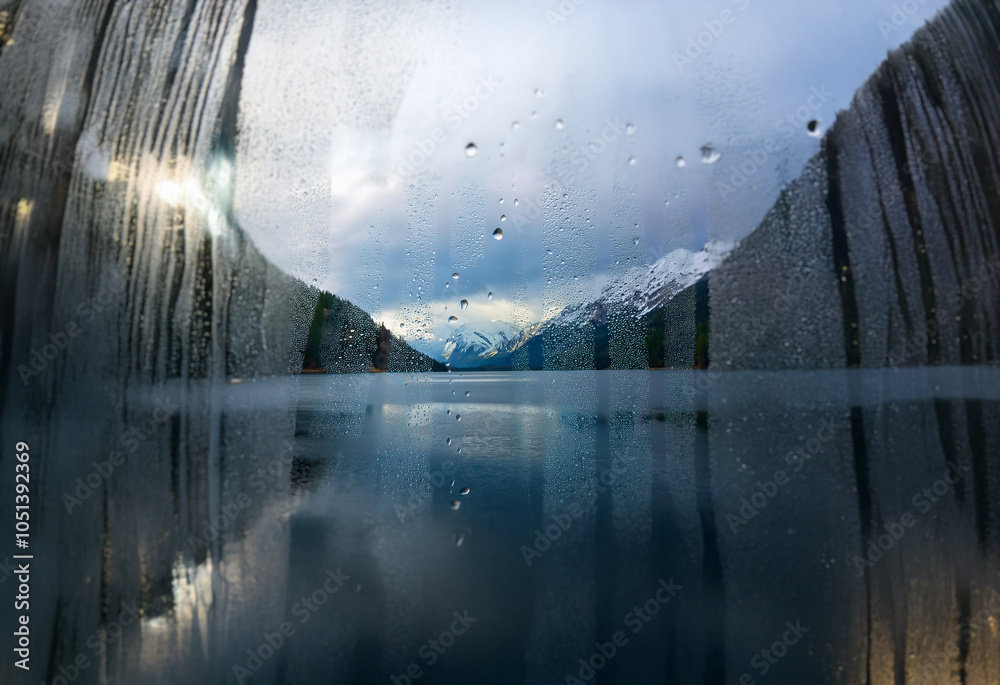 Poster A scenic mountain lake is viewed through a window with raindrops clinging to the glass.