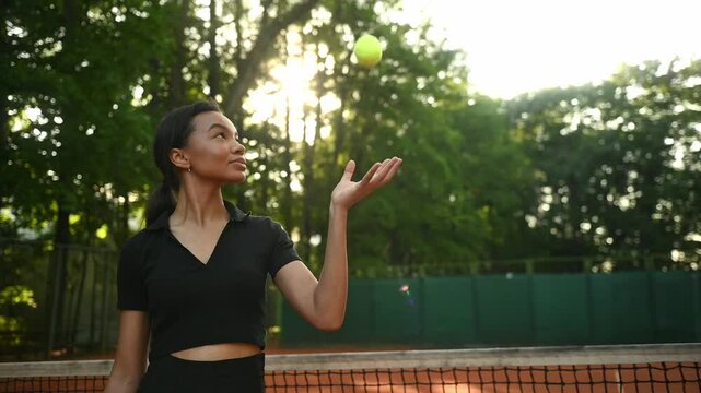A tennis player plays sports on a tennis court . The athlete trains in tennis. An African girl plays tennis. 