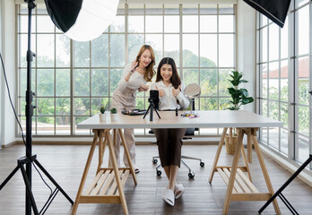 Two asian women creating content for social media. They are using a studio setup that include a...