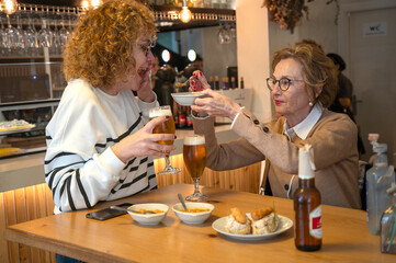 Two women, mother and daughter share a few laughs between drinks and appetizers