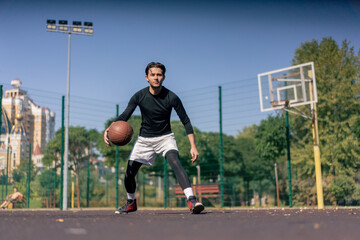 a sports ground basketball field active recreation guy in white shorts and black t-shirt plays basketball on camera different tricks