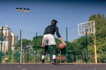 a sports ground basketball field active recreation guy in white shorts and black t-shirt plays basketball on camera different tricks