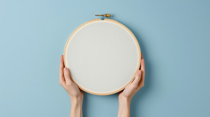 Embroidery Hoop Mockup:  A pair of hands delicately hold a blank embroidery hoop against a serene blue backdrop, offering a versatile canvas for creative projects and handcrafted designs.  