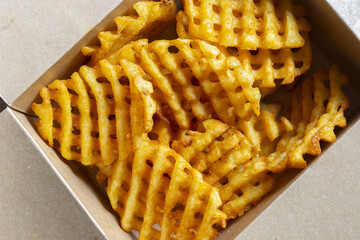 Waffle criss cross fries takeaway in a cardboard box. Biodegradable recycling environmentally...