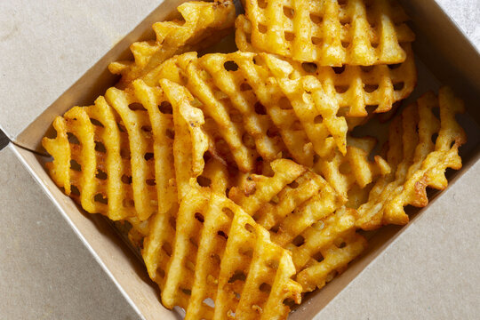 Waffle criss cross fries takeaway in a cardboard box. Biodegradable recycling environmentally friendly packaging