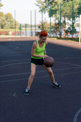Fototapeta premium sports ground basketball field active recreation girl with short hair in shorts and yellow T-shirt trains to throw basketball into the hoop training in agility