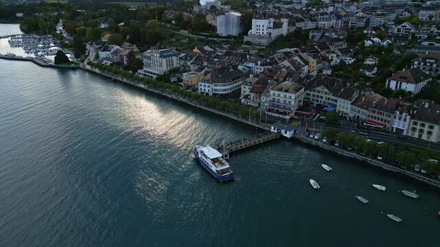 Orbit drone shot of Nyon pier with people embarking on a boat in Canton of Vaud Switzerland