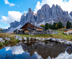 Fototapeta premium Discover the serene charm of a rustic cabin nestled by the Dolomites' majestic peaks in Italy