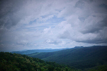 Obraz premium A stunning view of verdant mountains under a cloudy sky.