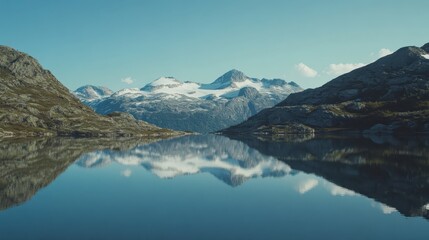 A sweeping mountain landscape with snow-capped peaks and a clear blue sky, a tranquil lake reflecting the entire scene.